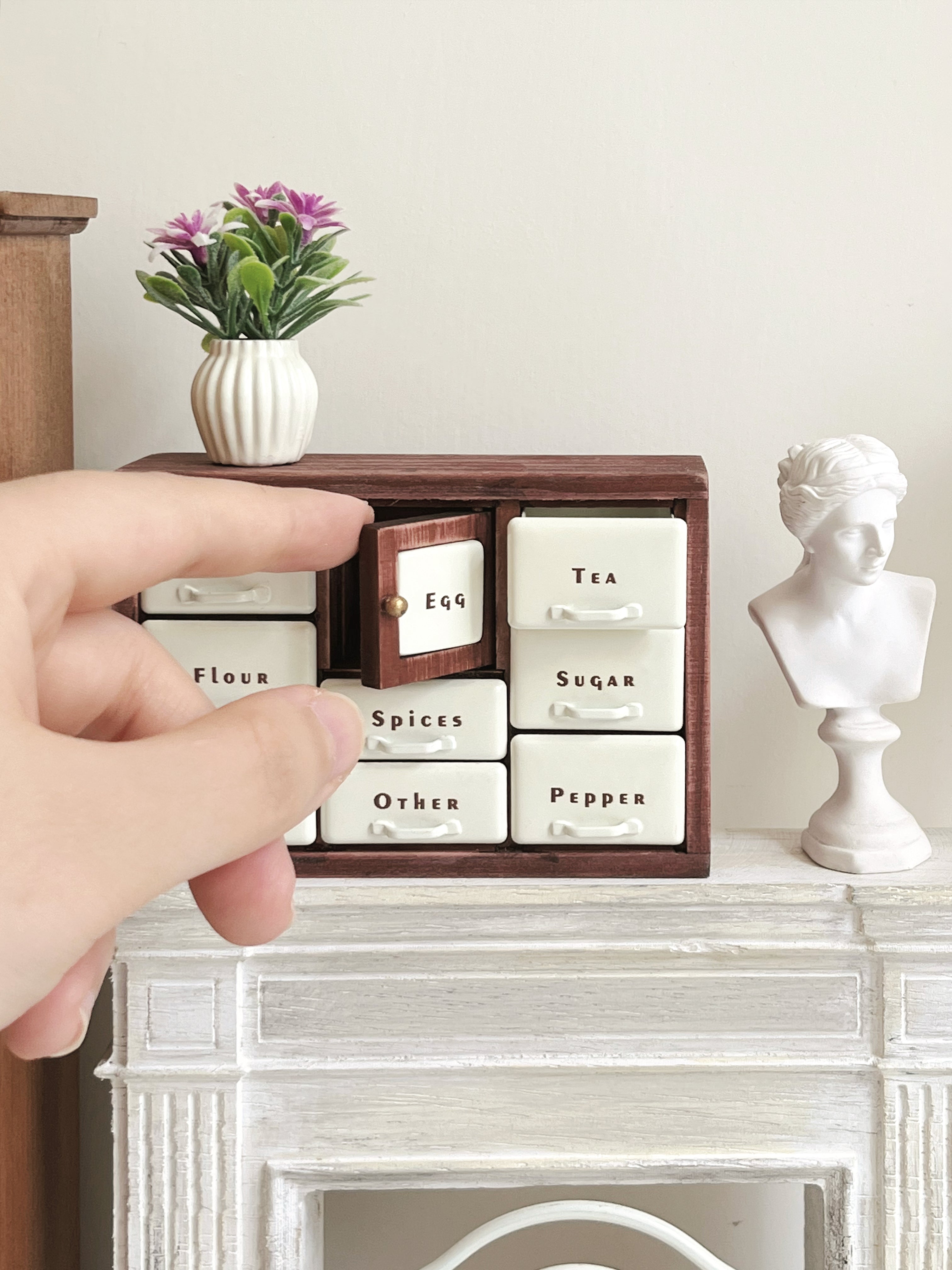 Red Bean spice cabinet on white fireplace mantel with center Egg door open
